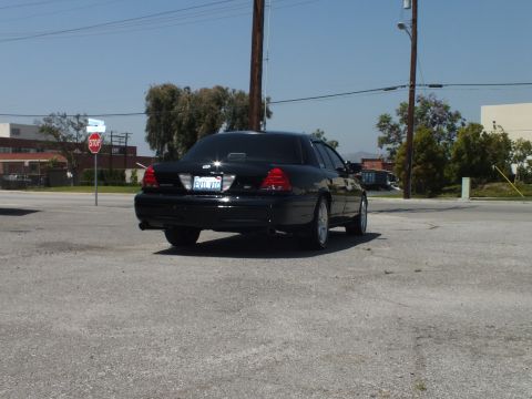 2003 Ford Crown Victoria - Direct rear shot of black Crown Victoria, dual exhaust and stop sign in background