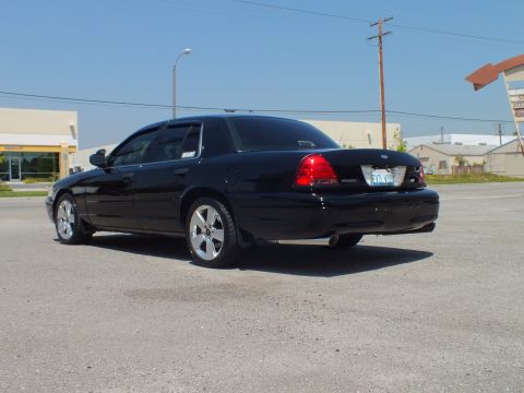 2003 Ford Crown Victoria - Rear-left angle of lowered black sedan, taillights lit, building and sign in background
