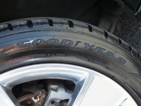 2003 Ford Crown Victoria - Close-up of Goodyear lettering on a low-profile tire with silver wheel and exposed brake rotor