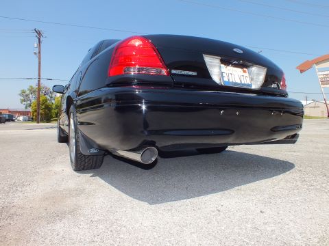 2003 Ford Crown Victoria - Ground-level rear shot of a black sedan with Ford oval, chrome exhaust tip and Ford-branded mud flap