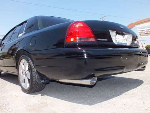 2003 Ford Crown Victoria - Low rear quarter view of a black sedan with Police Interceptor tail badge, Ford oval and chrome exhaust