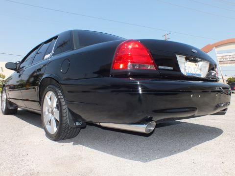 2003 Ford Crown Victoria - Black sedan rear quarter with tinted windows, silver multi-spoke wheel and chrome exhaust tip