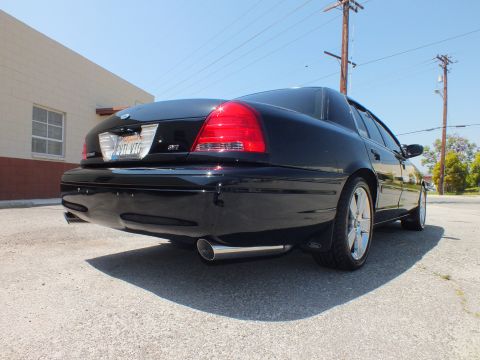 2003 Ford Crown Victoria - Ground-level rear quarter of a black sedan with SVT tail badge and single chrome exhaust outlet