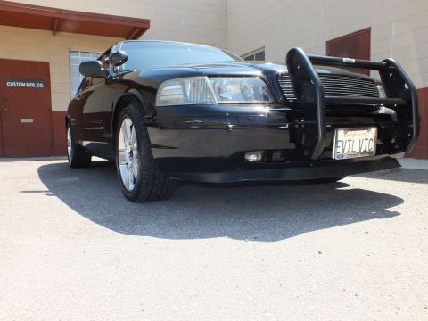 2003 Ford Crown Victoria - Ground-level front quarter of a black sedan with chrome push bumper and EVIL VTC California plate