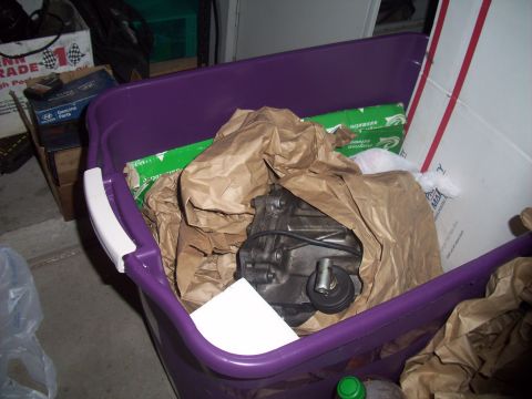 1995 Ford Probe - A car part is stored in a purple bin with other items, including boxes and packaging materials.
