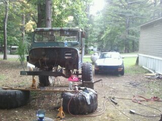 1978 Ford Bronco - A vintage Jeep CJ-5 is undergoing repairs outdoors, with a second vehicle visible in the background.