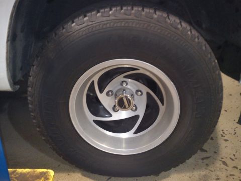 1997 Chevrolet Silverado 1500 - This image shows a close-up of a vehicle's wheel and tire, a distinctive silver alloy rim with a unique spoke pattern.