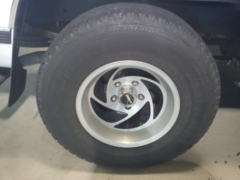 1997 Chevrolet Silverado 1500 - Close-up of a truck wheel and tire, showing a custom rim design. Supermotors.net logo is visible at the bottom.