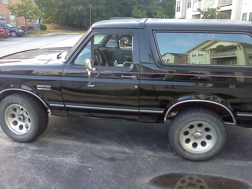 Black Ford Bronco side view, showing the driver's side door and rear quarter panel