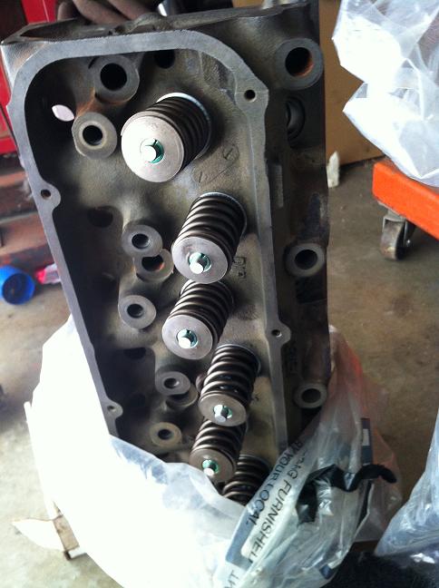 Cast iron cylinder head with installed valve springs on a workbench
