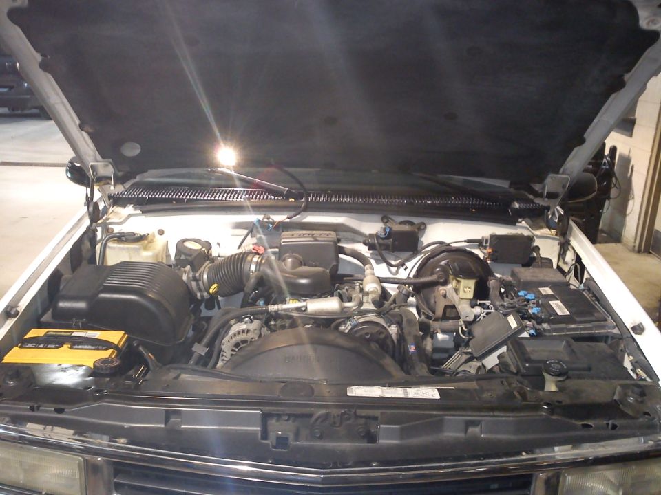 White 1997 Chevrolet Silverado 1500 engine bay with hood open, showing V8 engine components and battery