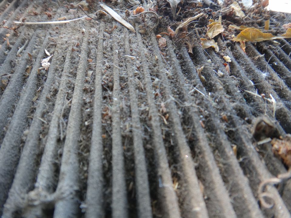 Dirty air filter covered in dust, leaves, and debris