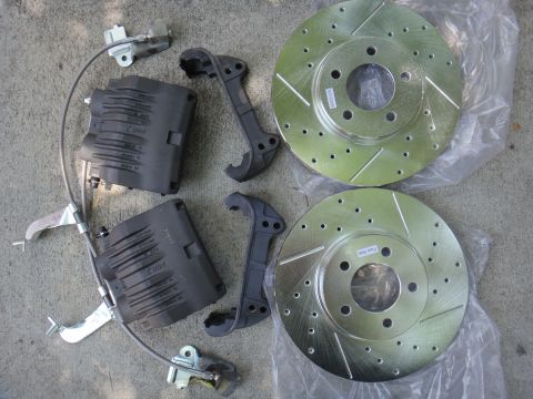 2003 Ford Taurus - Aftermarket brake components, including rotors and calipers, are laid out on a gray concrete surface.