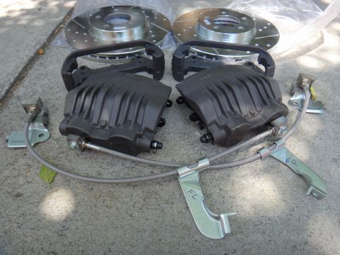 2003 Ford Taurus - Aftermarket brake calipers and rotors are laid out on a concrete surface, ready for installation.