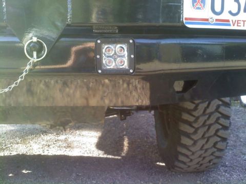 1996 Ford Bronco - Close-up of a black rear bumper an LED light and a tow ring, with a large tire visible.