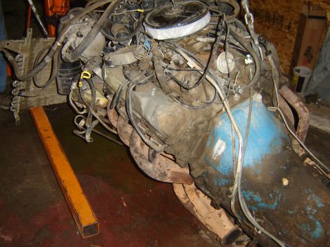 1982 Mercury Zephyr - A V8 engine assembly, possibly out of a vehicle, is suspended by a chain hoist.