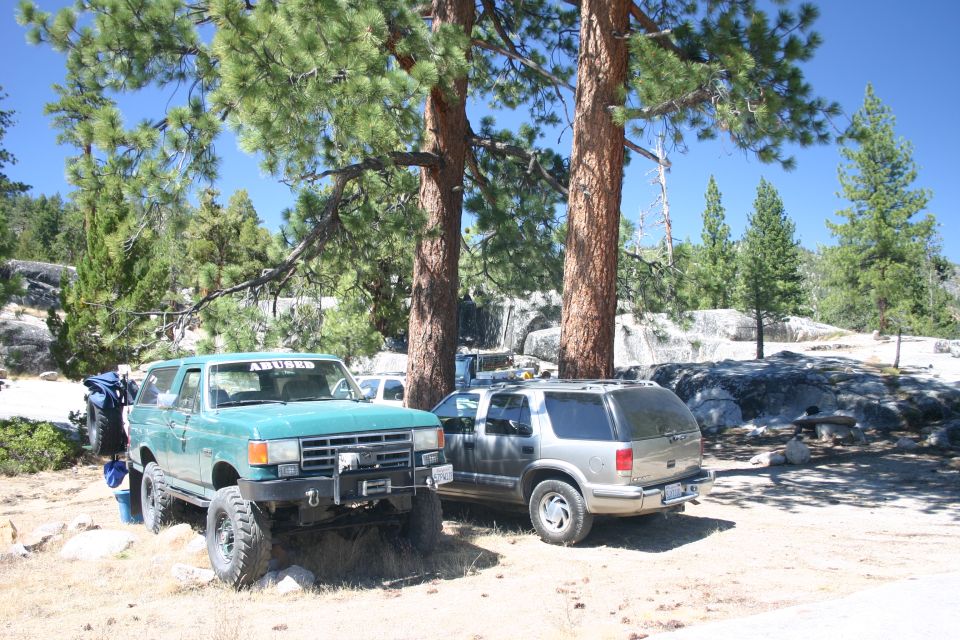 Green 1991 Ford Bronco with off-road tires and winch, parked next to a silver SUV