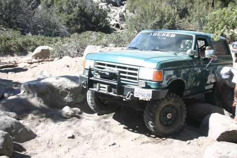 1991 Ford Bronco - 1991 Ford Bronco tackling off-road obstacles on a sunny day.