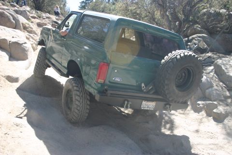 1991 Ford Bronco - 1991 Ford Bronco tackling a challenging off-road course on a sunny day.