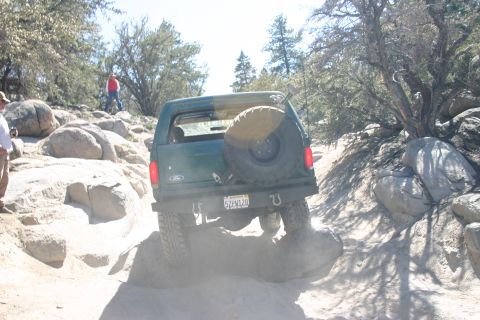 1991 Ford Bronco - This 1991 Ford Bronco navigates a challenging off-road path with large rocks and trees.