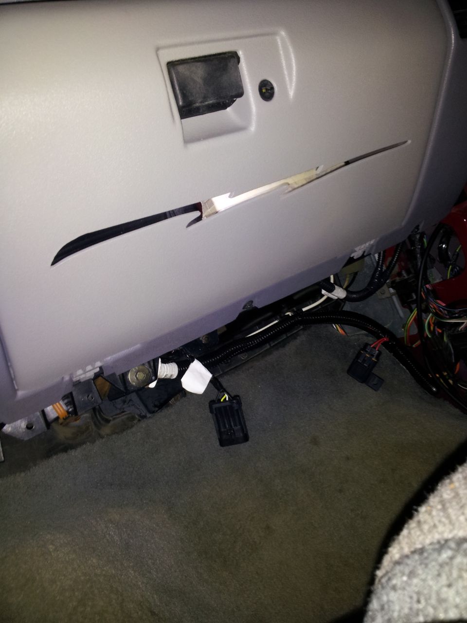 Vehicle interior showing a damaged glove compartment and exposed wiring under the dashboard
