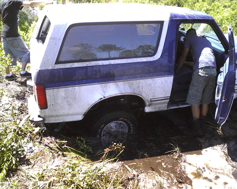 1996 Ford Bronco stuck in mud with people around it