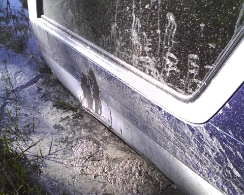 1996 Ford Bronco - The vehicle appears to be stuck in a muddy, wet environment, with visible damage to its side panel.