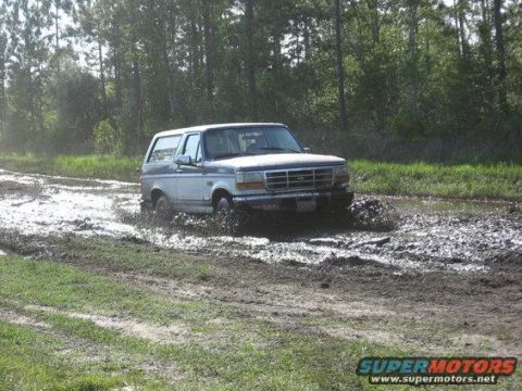 1996 Ford Bronco - Ford Bronco navigates a muddy track surrounded by trees.