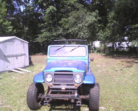 1969 Toyota Land Cruiser - Front view of a blue 1969 Toyota Land Cruiser parked in a grassy yard with a shed in the background.