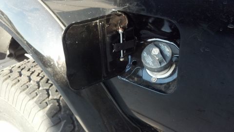 1995 Ford Bronco - The fuel door is open, revealing the gas cap and part of the tire.