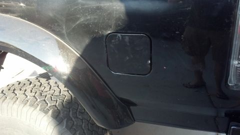 1995 Ford Bronco - Side view of a black SUV's rear quarter panel, showing the fuel door and tire.