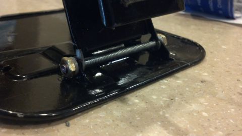1995 Ford Bronco - Black metal bracket with bolt and nuts, likely a component for a vehicle.