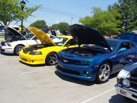 2007 Ford Mustang - Several cars are lined up with their hoods open at an outdoor event. The yellow car is a Ford Mustang.