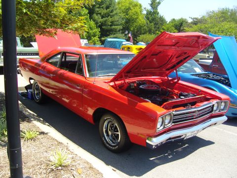 2007 Ford Mustang - A red 1969 Plymouth Road Runner is displayed with its hood open at an outdoor car show.