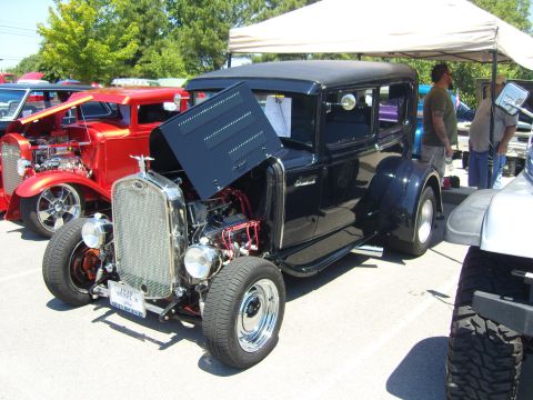 2007 Ford Mustang - A black hot rod with its hood open, parked next to a red hot rod and a white Jeep. The license plate indicates it is a 1930 Model A.