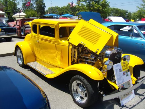 2007 Ford Mustang - A yellow hot rod coupe is displayed with its hood open, revealing the engine. A sign is placed in front of the vehicle.
