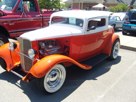 2007 Ford Mustang - A two-tone hot rod coupe is parked next to a red pickup truck and a blue car.