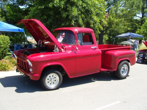 2007 Ford Mustang - A classic red Chevrolet pickup truck is displayed with its hood open at an outdoor event.