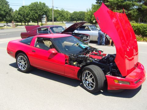 2007 Ford Mustang - Multiple vehicles are parked outdoors, one with its hood open, revealing the engine.