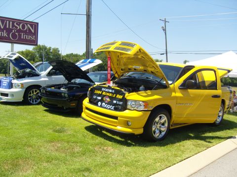 2007 Ford Mustang - A yellow 2004 Dodge Ram Rumble Bee pickup truck is displayed with its hood open at a car show.