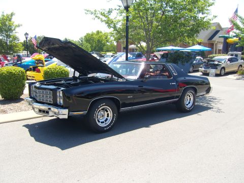 2007 Ford Mustang - A black 1973 Chevrolet Monte Carlo is displayed with its hood open at an outdoor event.