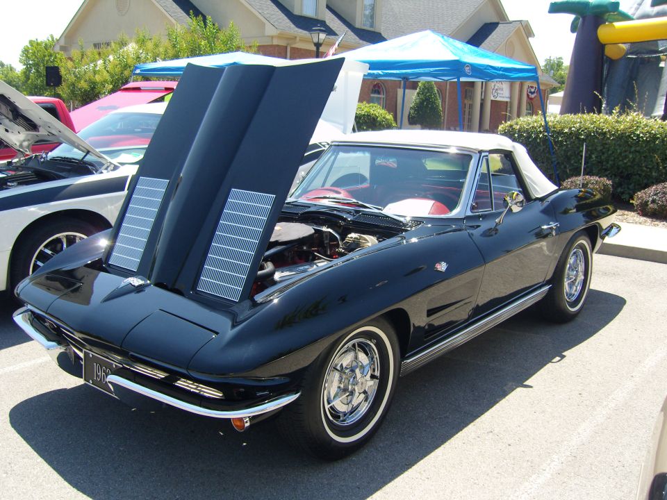 Black convertible with hood open, red interior, and chrome wheels. License plate reads "1963"
