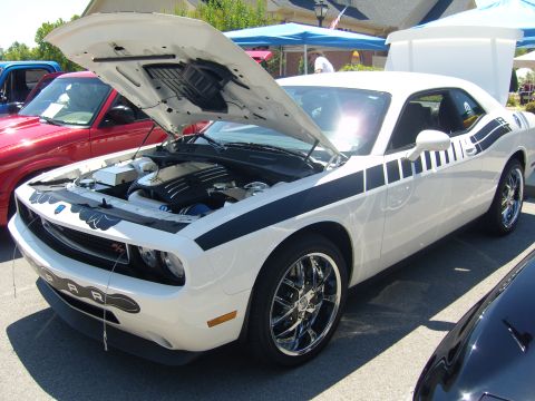 2007 Ford Mustang - A white 2008 Dodge Challenger with black racing stripes is displayed with its hood open, revealing the engine bay.