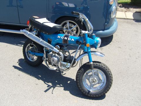 2007 Ford Mustang - A blue Honda Trail 70 motorcycle is parked in front of a blue van at a car show.