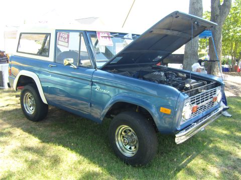 2007 Ford Mustang - This classic Ford Bronco is displayed with its hood up, revealing the engine bay. It has 'For Sale' signs in the windows.