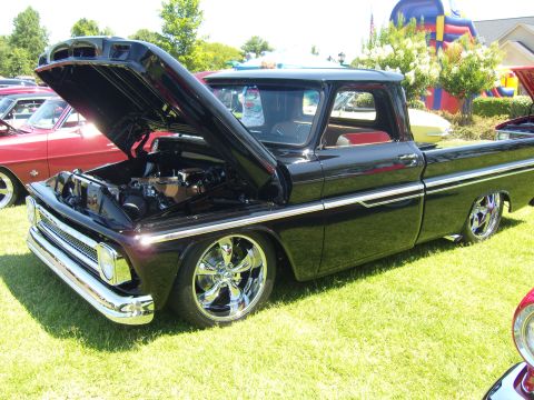 2007 Ford Mustang - Customized black pickup truck from the 1960s displayed at an outdoor car show.
