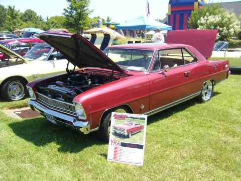 2007 Ford Mustang - A classic red 1966 Nova SS is displayed with its hood open at an outdoor event, with other vehicles and tents in the background.