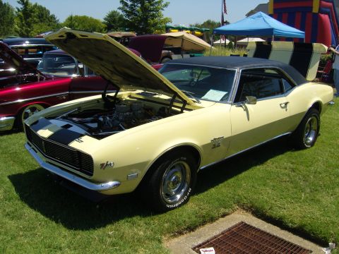2007 Ford Mustang - A yellow 1968 Chevrolet Camaro SS is displayed with its hood open at an outdoor event.