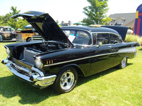 2007 Ford Mustang - A classic black Chevrolet sedan is displayed with its hood open at a sunny outdoor gathering.