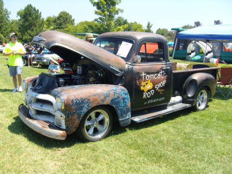 2007 Ford Mustang - A vintage pickup truck with extensive rust and custom modifications sits on display at an outdoor event.